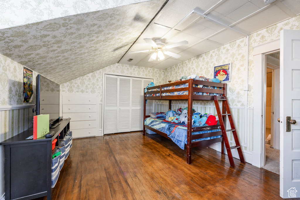 Bedroom featuring dark hardwood / wood-style flooring, vaulted ceiling, a closet, and ceiling fan
