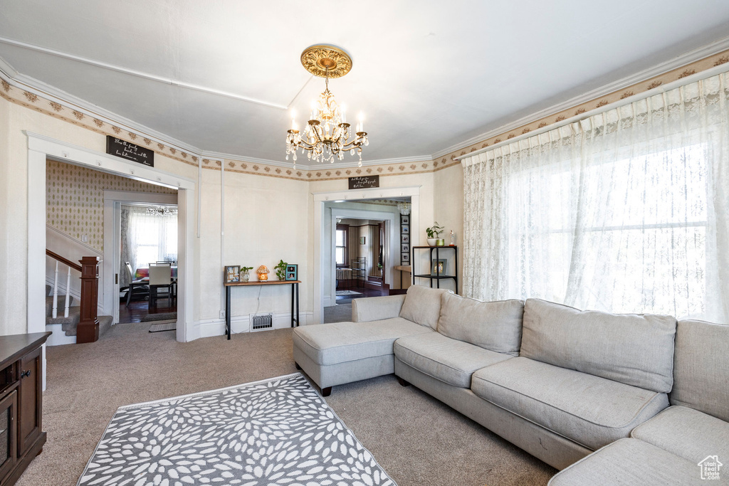 Living room with light carpet, a notable chandelier, and crown molding
