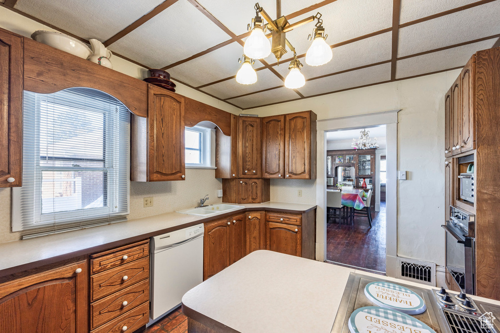 Kitchen with black oven, sink, hanging light fixtures, white dishwasher, and an inviting chandelier