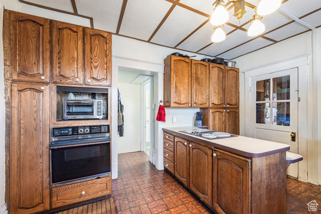 Kitchen with an inviting chandelier, stainless steel gas stovetop, and black oven