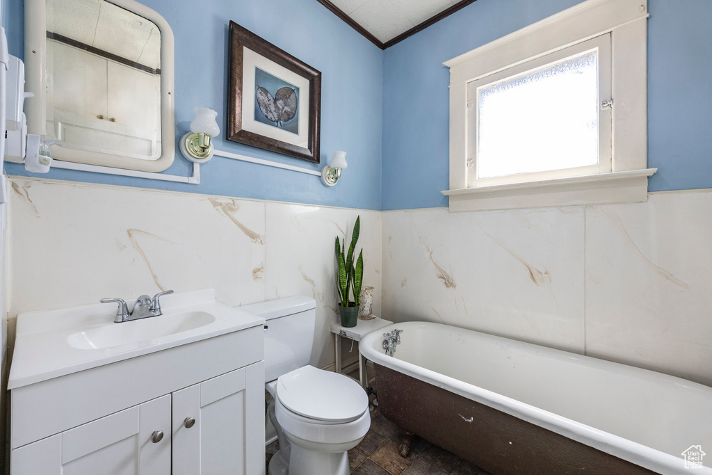 Bathroom featuring a bathing tub, vanity, crown molding, and toilet