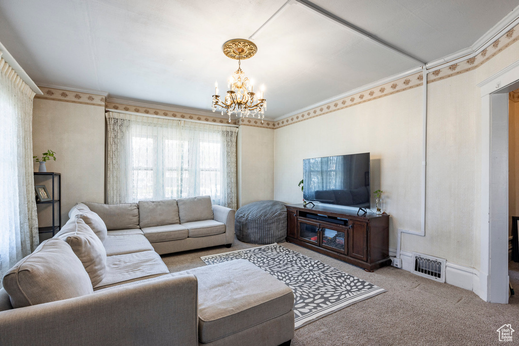 Living room featuring crown molding, light carpet, and a notable chandelier