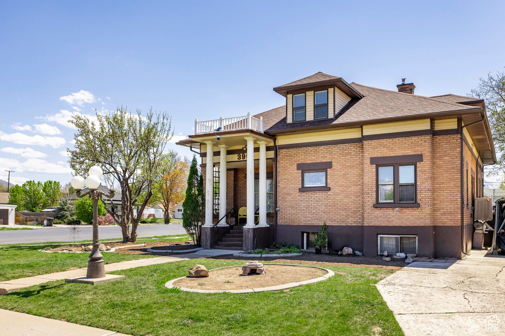 View of front of house with a front yard and a balcony