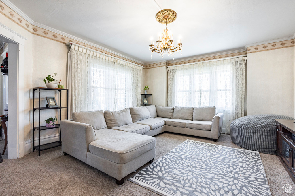Carpeted living room featuring ornamental molding and a chandelier