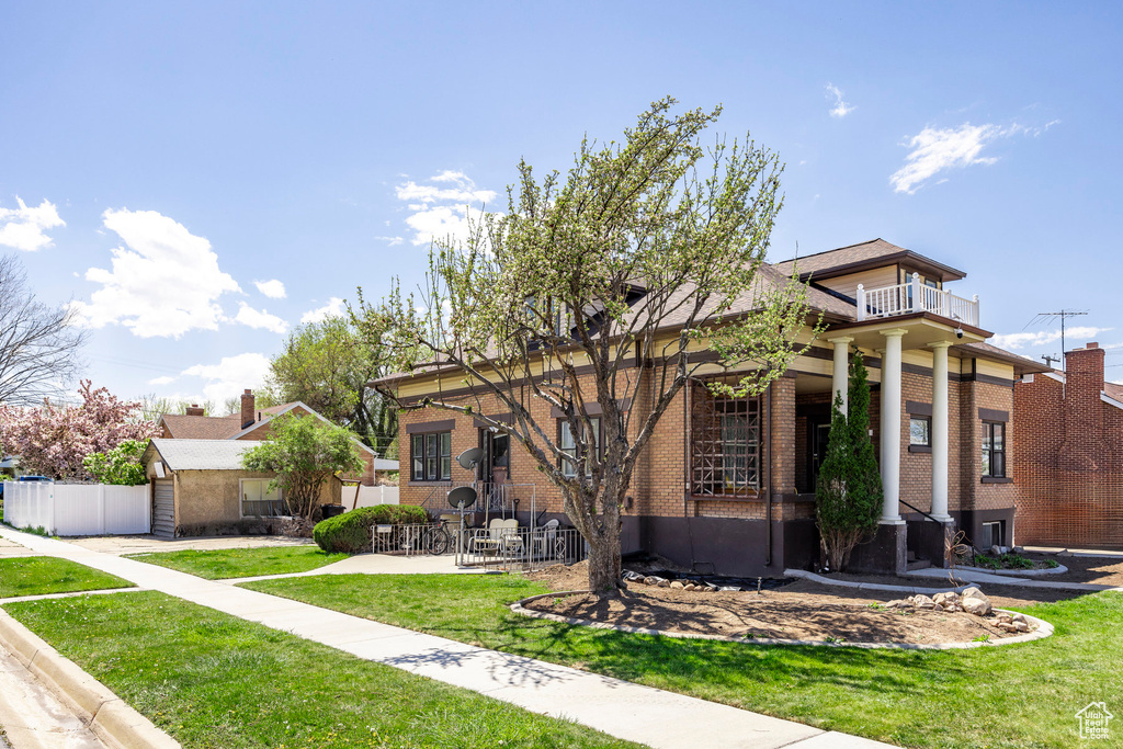View of front facade with a balcony and a front yard