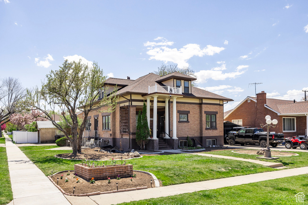View of front facade featuring a balcony and a front lawn