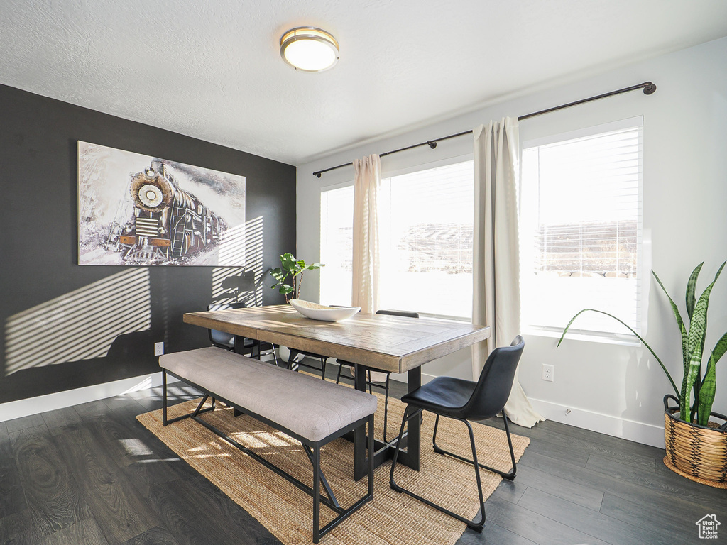 Dining area with dark wood-type flooring, a wealth of natural light, and a textured ceiling