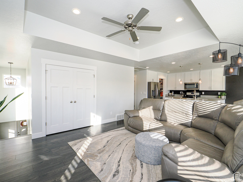 Living room featuring dark wood-type flooring and ceiling fan