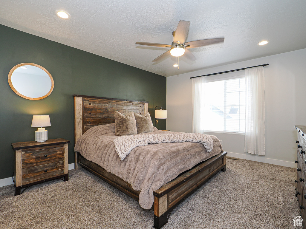 Bedroom featuring ceiling fan, carpet floors, and a textured ceiling