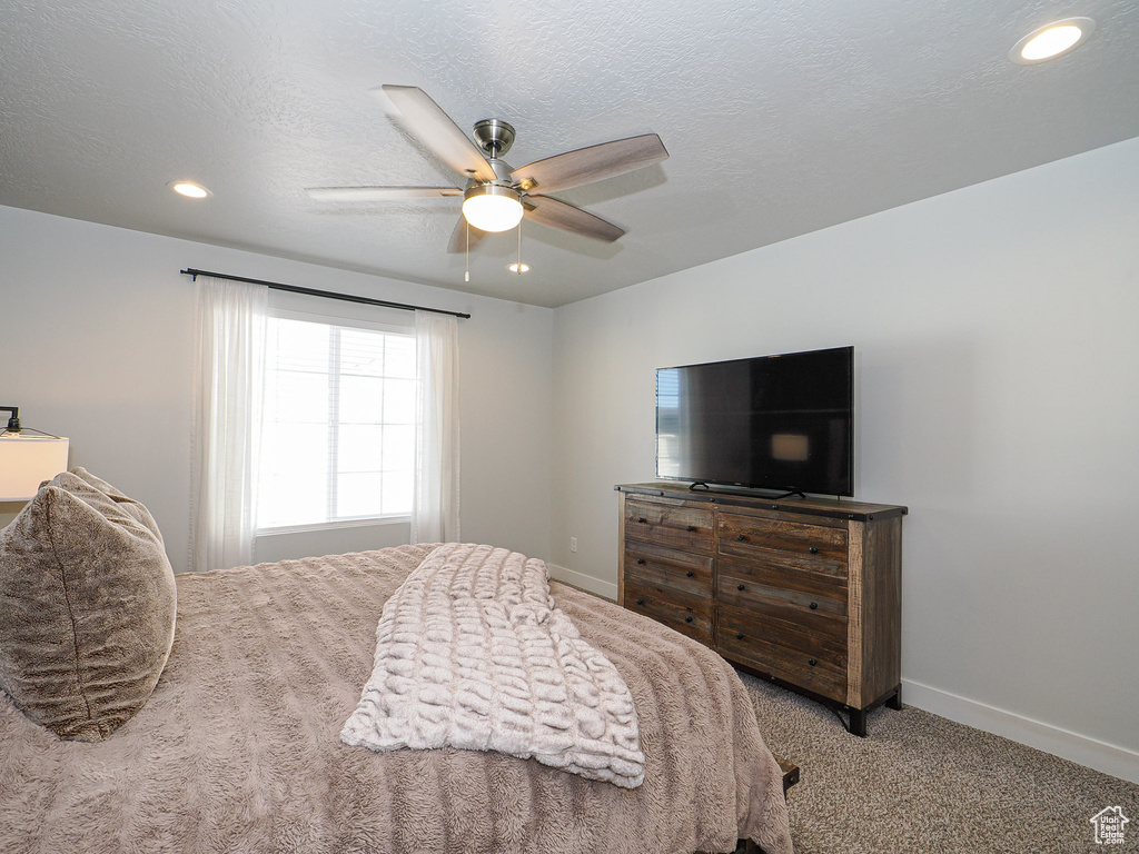 Bedroom featuring ceiling fan, carpet flooring, and a textured ceiling