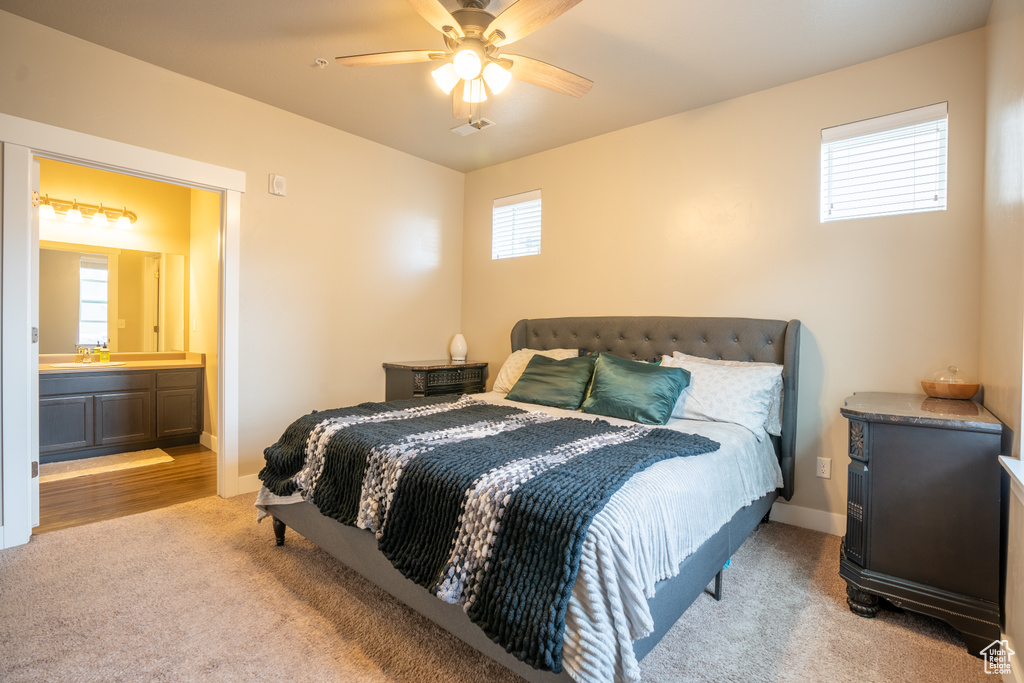 Bedroom with sink, light colored carpet, ceiling fan, and ensuite bathroom