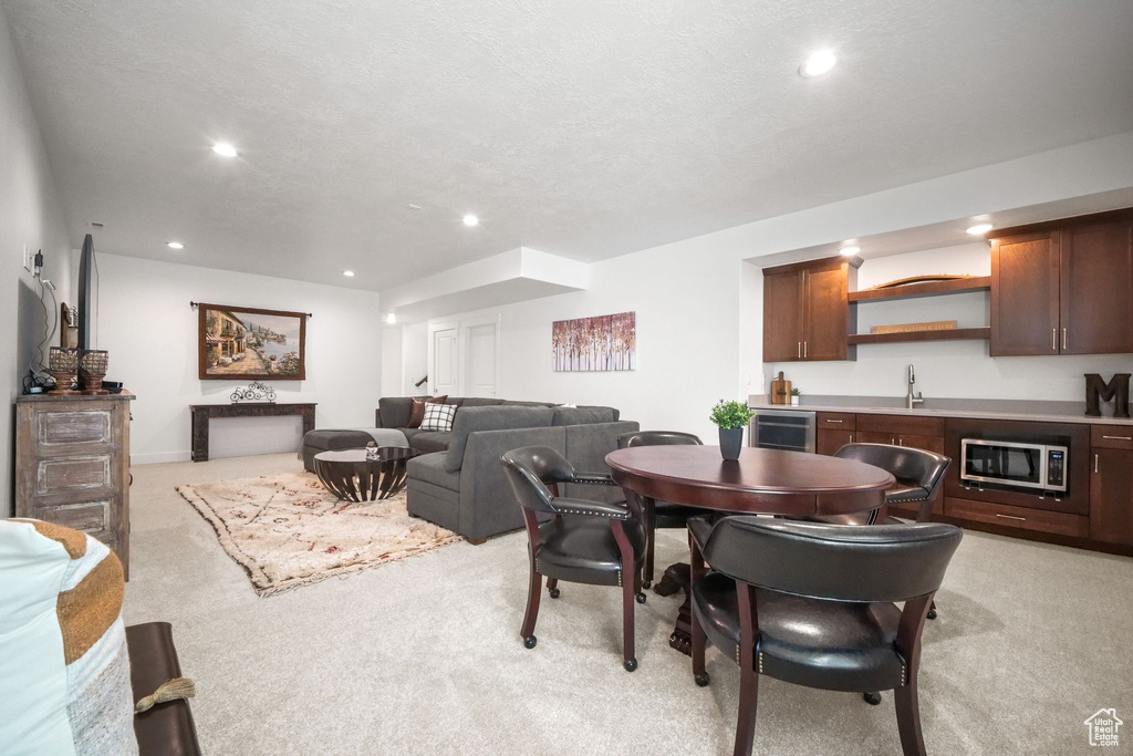 Dining room featuring light carpet, wine cooler, a textured ceiling, and wet bar