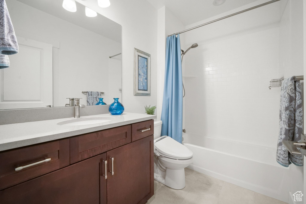 Full bathroom featuring shower / tub combo with curtain, vanity, toilet, and tile patterned floors