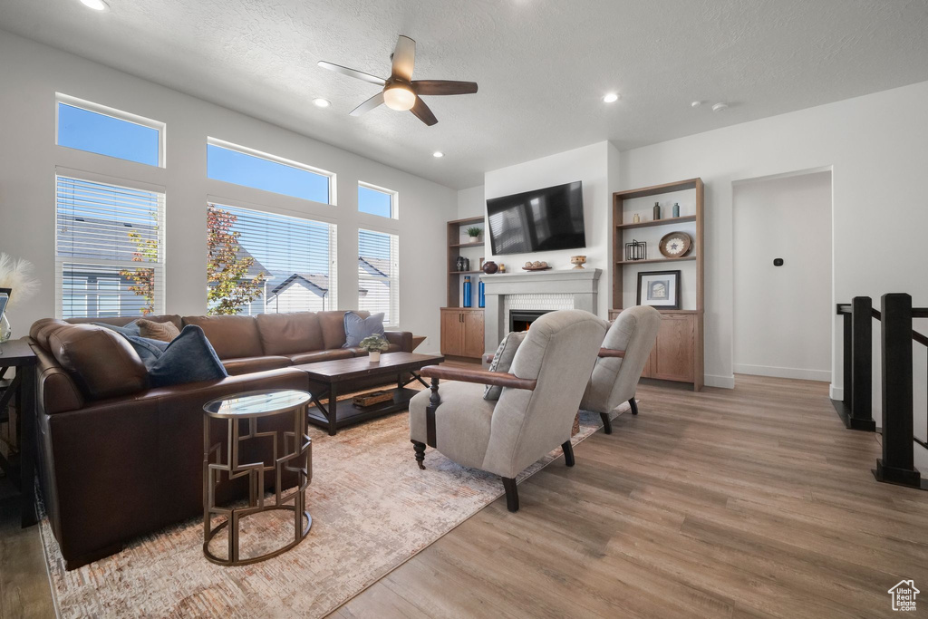 Living room with ceiling fan, light hardwood / wood-style floors, and a textured ceiling