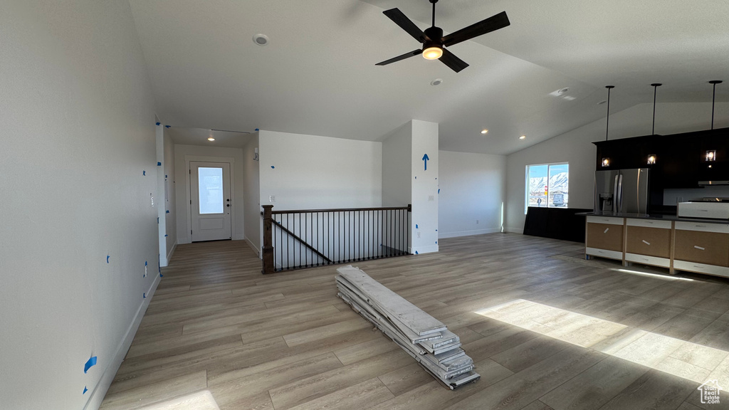 Kitchen with lofted ceiling, hanging light fixtures, light hardwood / wood-style flooring, stainless steel fridge, and ceiling fan