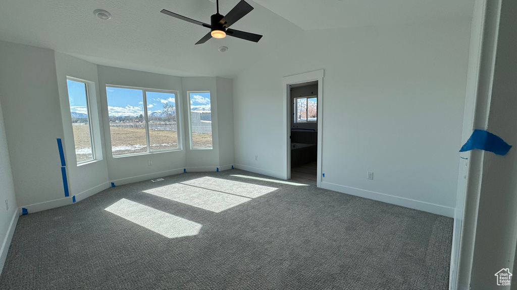 Spare room with ceiling fan, lofted ceiling, and dark carpet