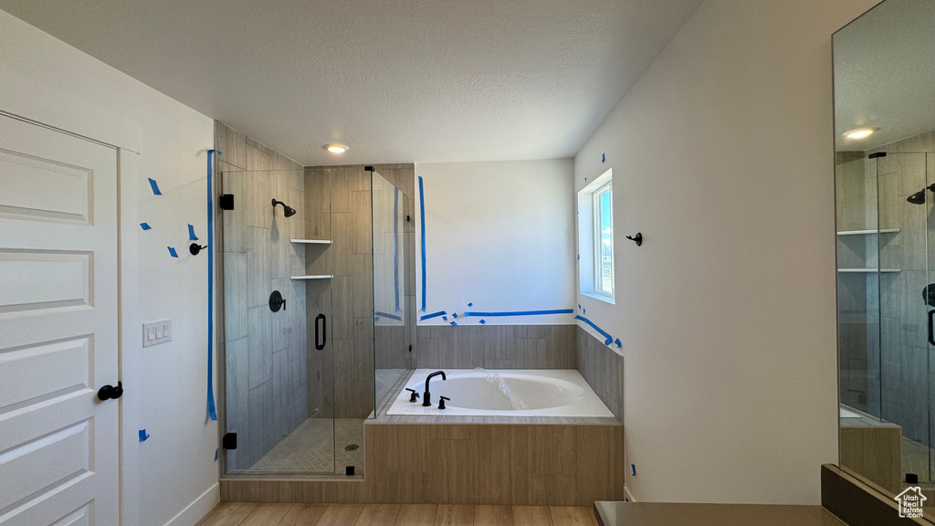 Bathroom featuring wood-type flooring, separate shower and tub, and a textured ceiling