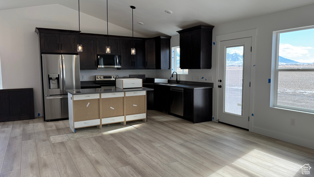 Kitchen with pendant lighting, sink, stainless steel appliances, a kitchen island, and light wood-type flooring