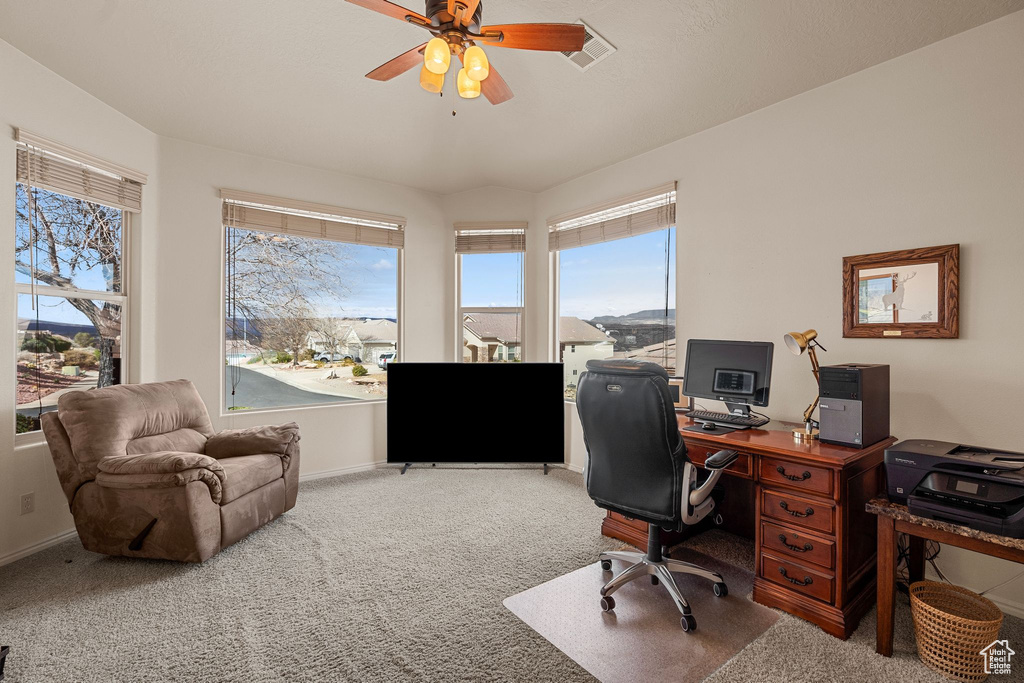 Carpeted office with plenty of natural light and ceiling fan