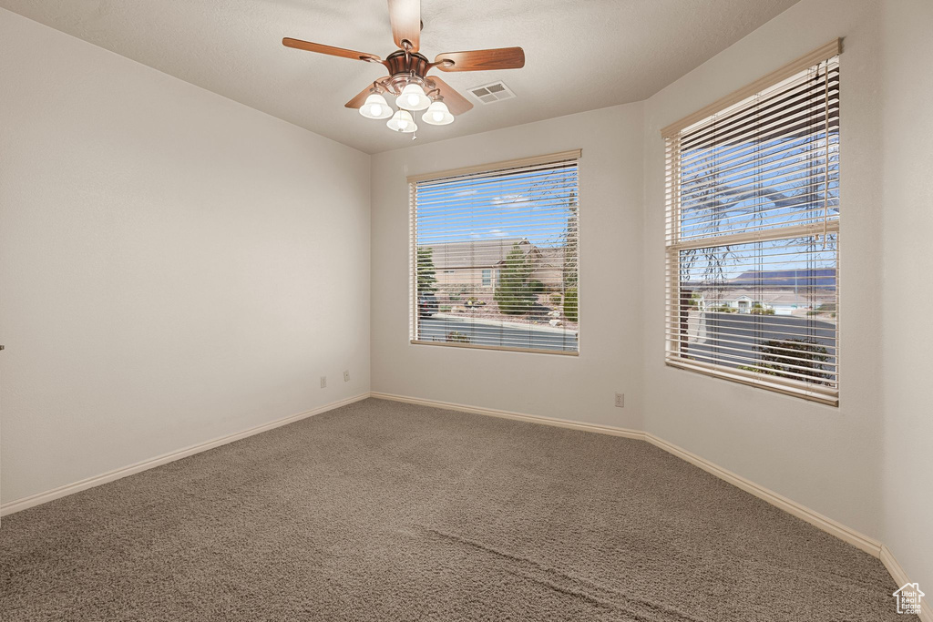 Carpeted spare room featuring ceiling fan