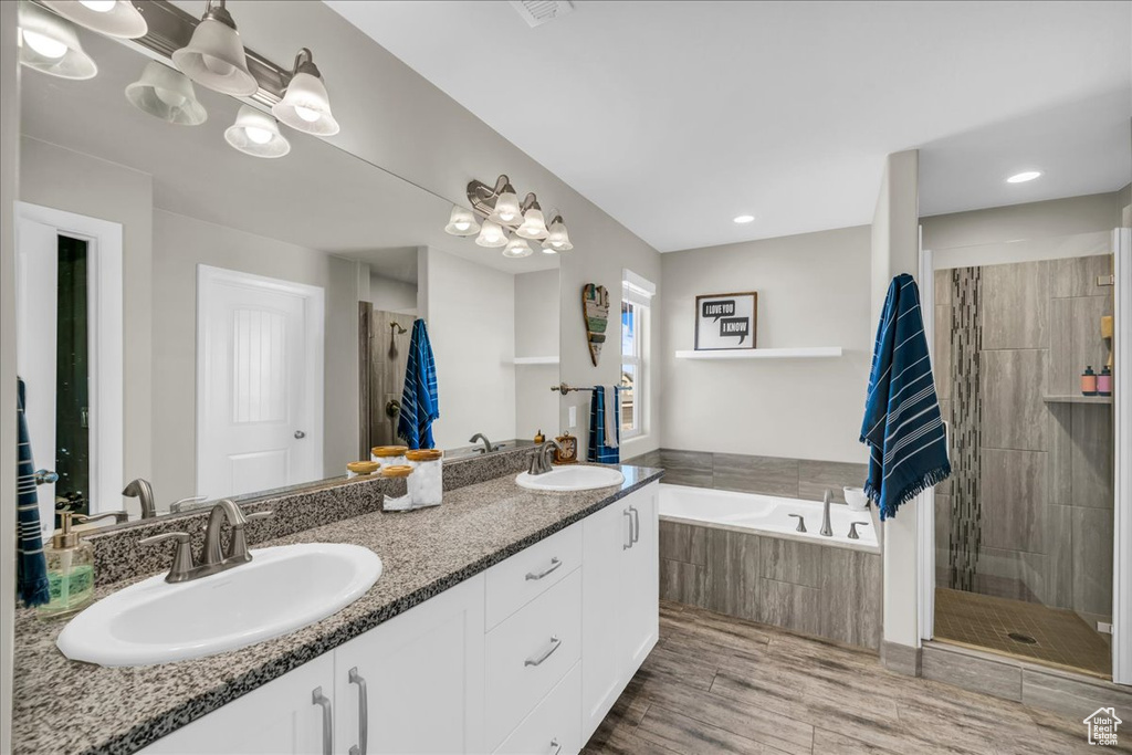 Bathroom with a notable chandelier, plus walk in shower, wood-type flooring, and vanity