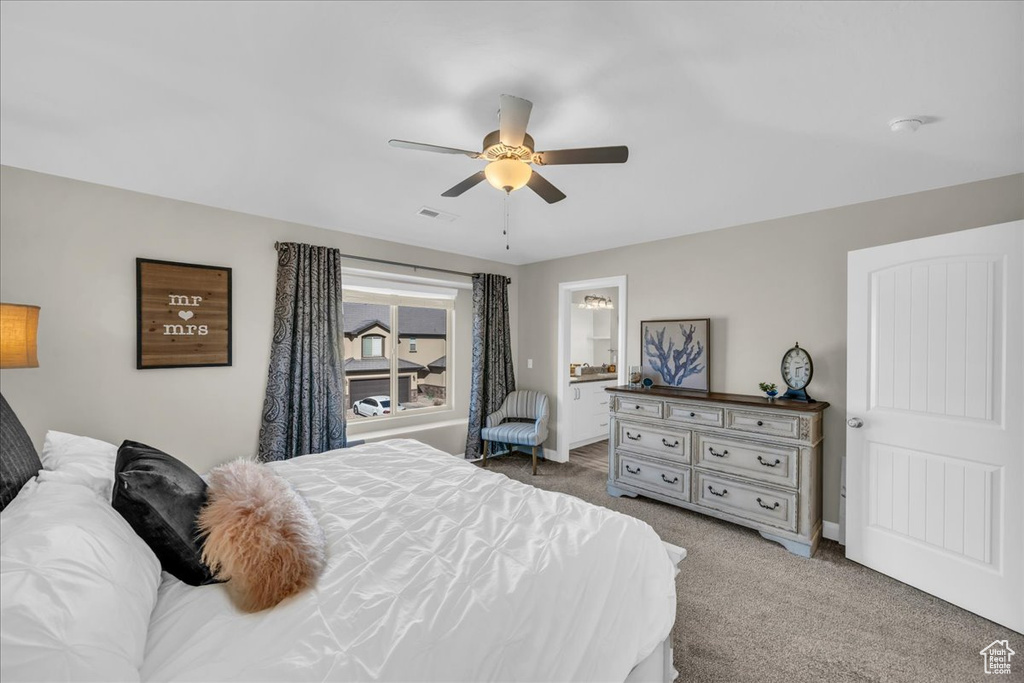 Bedroom with ensuite bathroom, carpet, and ceiling fan