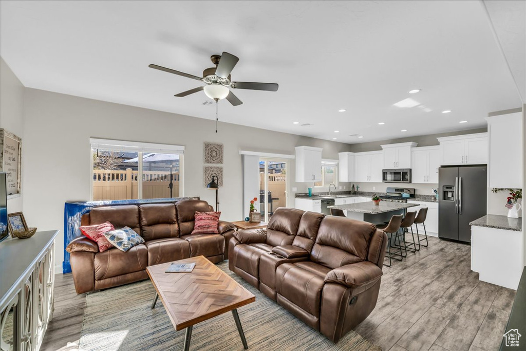 Living room with ceiling fan and light hardwood / wood-style floors