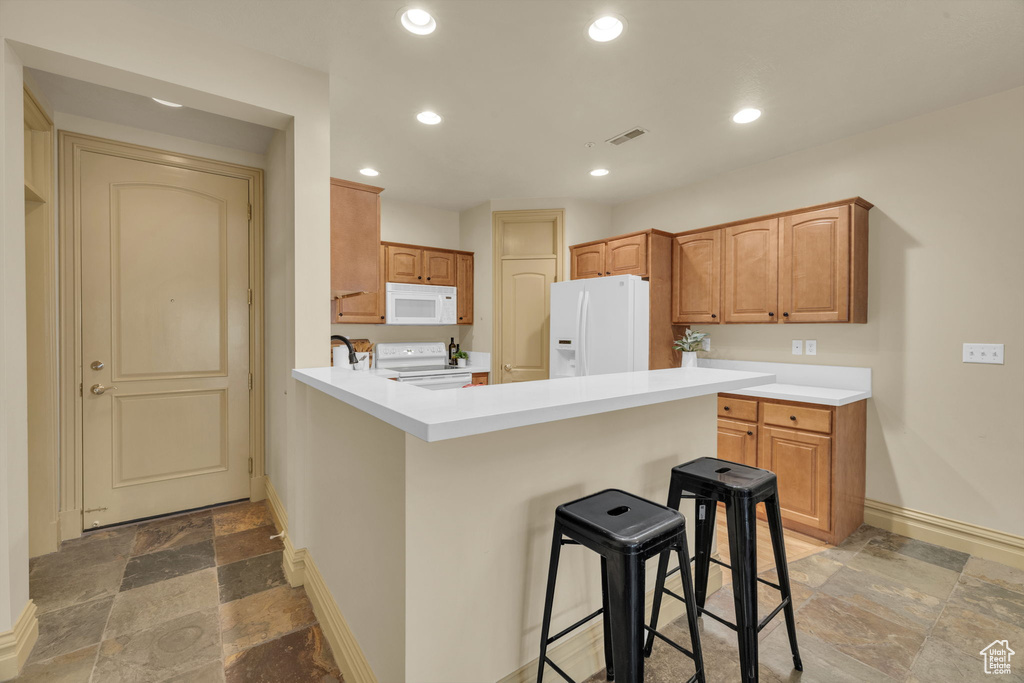 Kitchen featuring white appliances, a kitchen breakfast bar, and kitchen peninsula