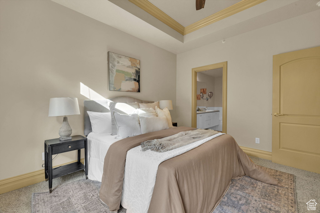 Bedroom featuring crown molding, light carpet, connected bathroom, and a tray ceiling