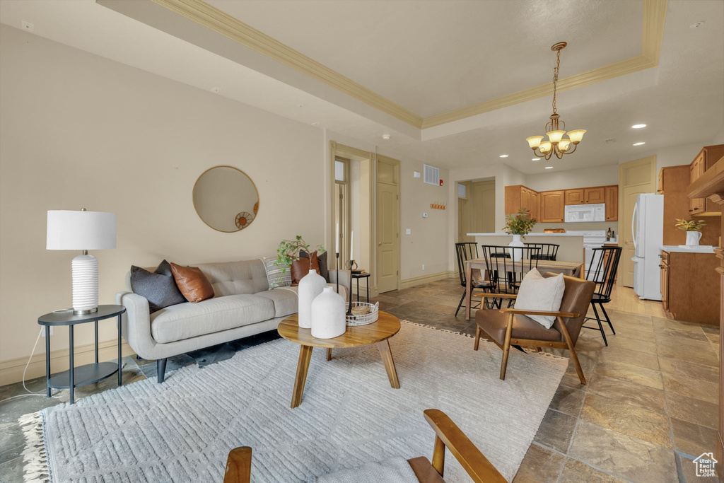 Living room featuring a notable chandelier, crown molding, and a raised ceiling