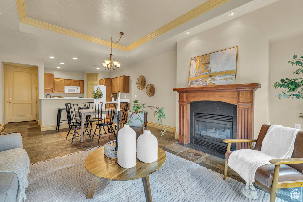 Living room featuring a raised ceiling, crown molding, and an inviting chandelier