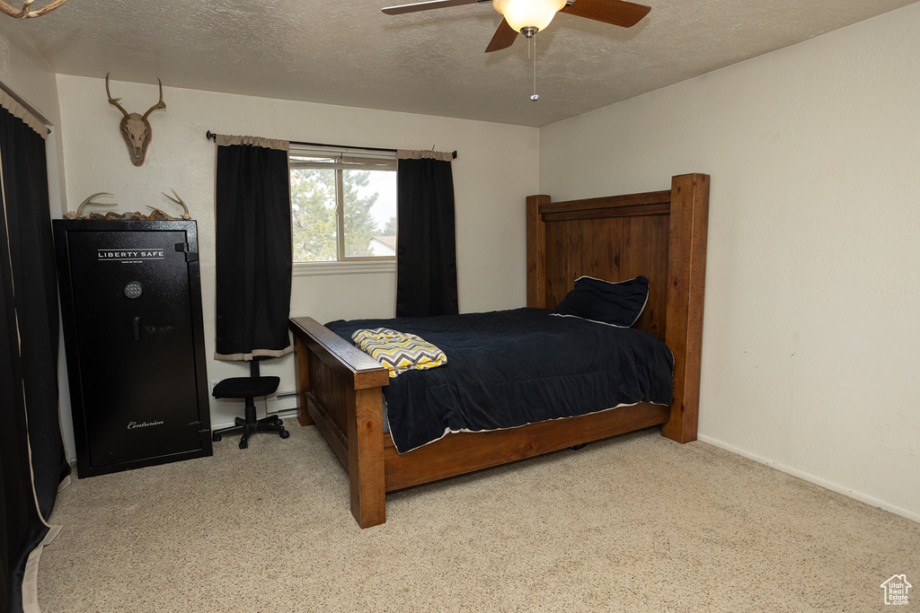 Carpeted bedroom with ceiling fan and a textured ceiling