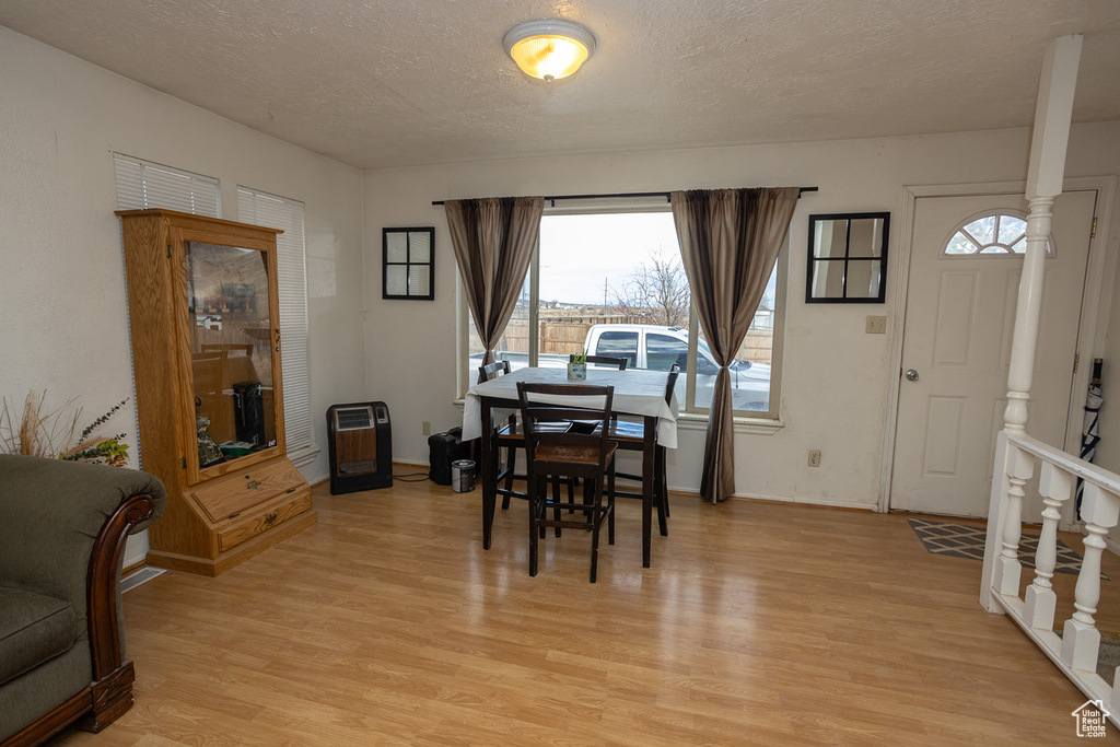 Dining area featuring heating unit, light hardwood / wood-style floors, and a textured ceiling