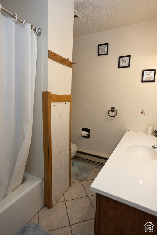 Full bathroom featuring vanity, a textured ceiling, a baseboard radiator, tile patterned floors, and shower / bath combo with shower curtain