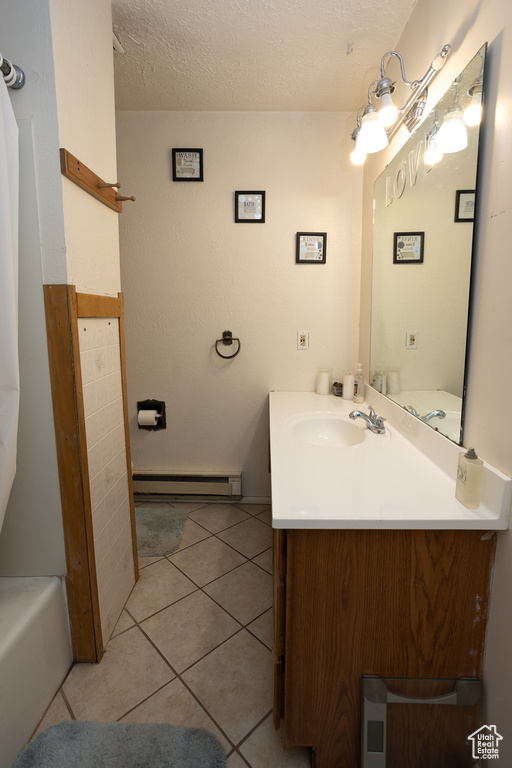 Bathroom featuring a baseboard heating unit, vanity, a textured ceiling, a tub to relax in, and tile patterned floors