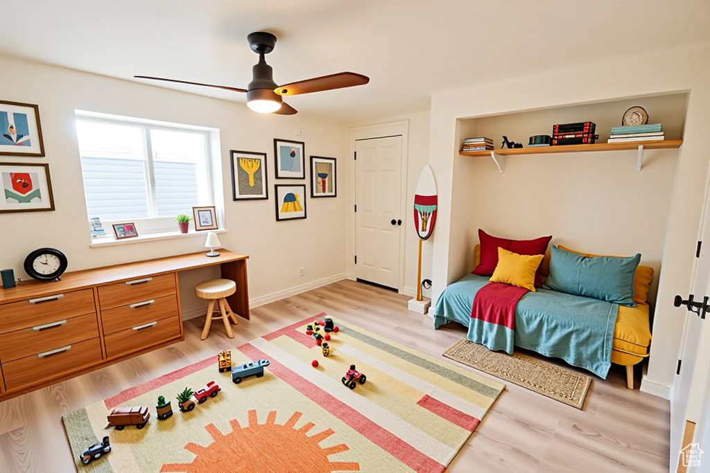 Recreation room with light wood-style flooring, a ceiling fan, and baseboards