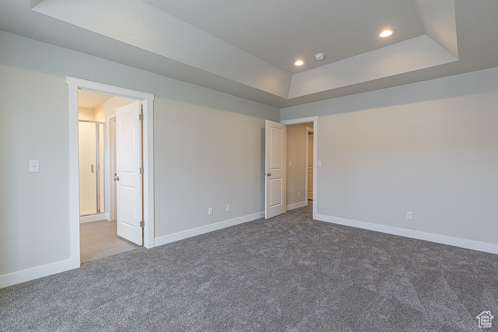 Carpeted empty room with baseboards, a tray ceiling, and recessed lighting