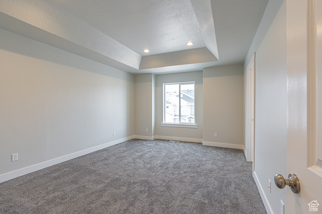 Spare room with carpet floors, baseboards, recessed lighting, a raised ceiling, and a textured ceiling