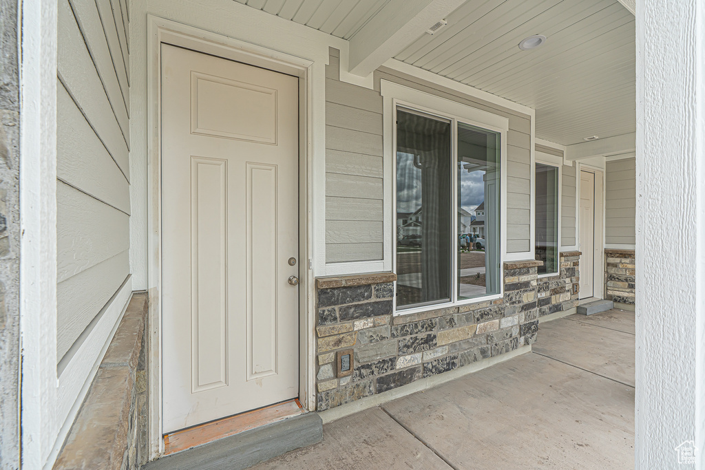 Property entrance featuring covered porch and stone siding