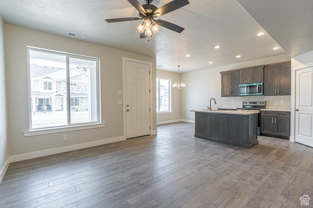 Kitchen with a textured ceiling, stainless steel appliances, baseboards, recessed lighting, and visible vents