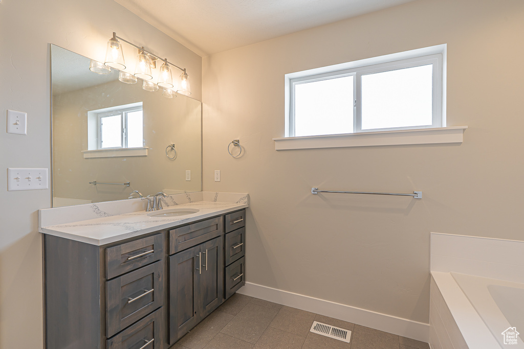 Full bathroom featuring baseboards, a bath, visible vents, and vanity