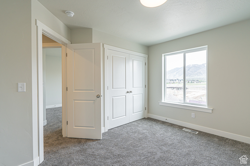 Unfurnished bedroom with carpet flooring, baseboards, visible vents, and a mountain view