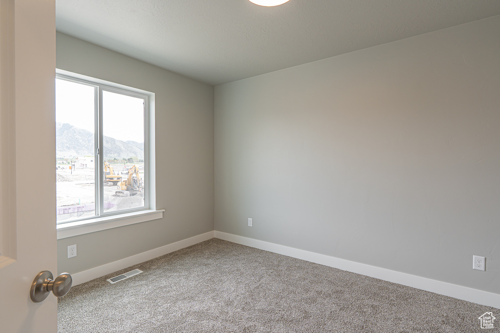 Empty room featuring plenty of natural light, carpet flooring, a mountain view, and visible vents
