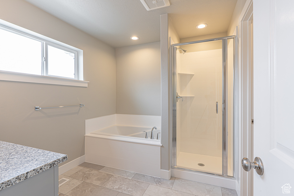 Bathroom featuring a bath, visible vents, a stall shower, vanity, and baseboards