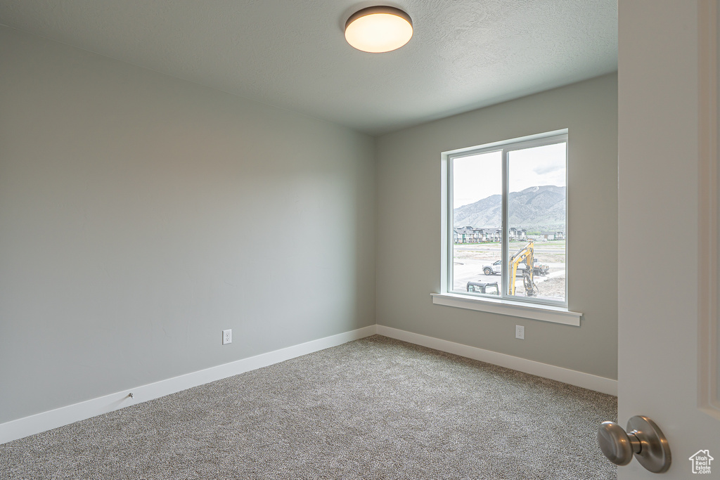 Spare room featuring carpet floors, baseboards, and a mountain view