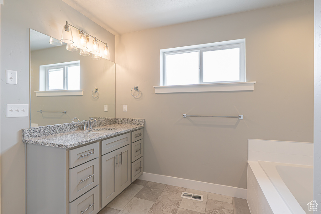 Full bath featuring visible vents, baseboards, a bathtub, and vanity
