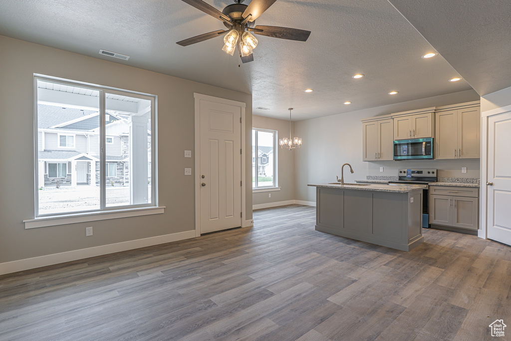 Kitchen with a textured ceiling, wood finished floors, a sink, stainless steel appliances, and recessed lighting