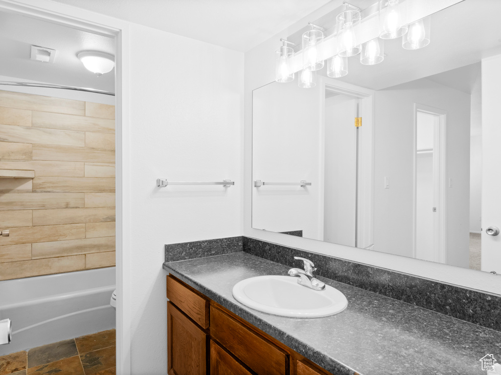 Full bathroom featuring vanity, tiled shower / bath combo, and toilet