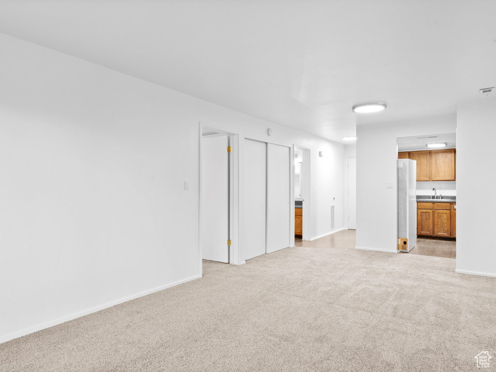 Empty room featuring sink and light colored carpet
