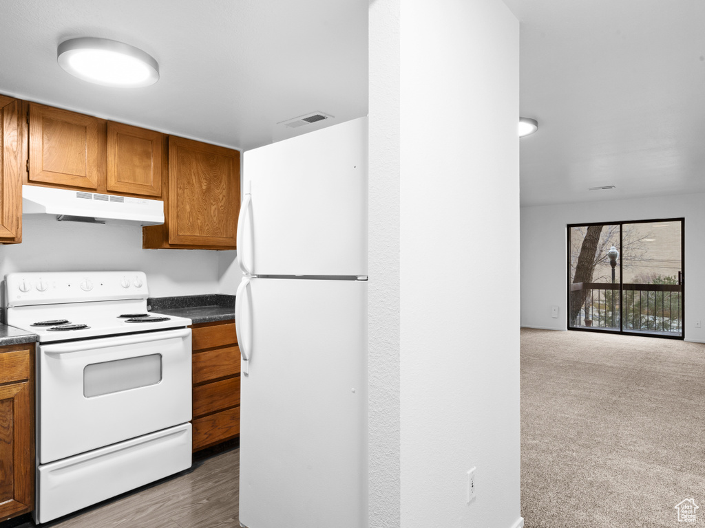 Kitchen featuring white appliances and dark colored carpet